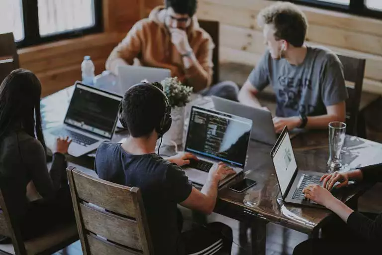 students around a table with computers